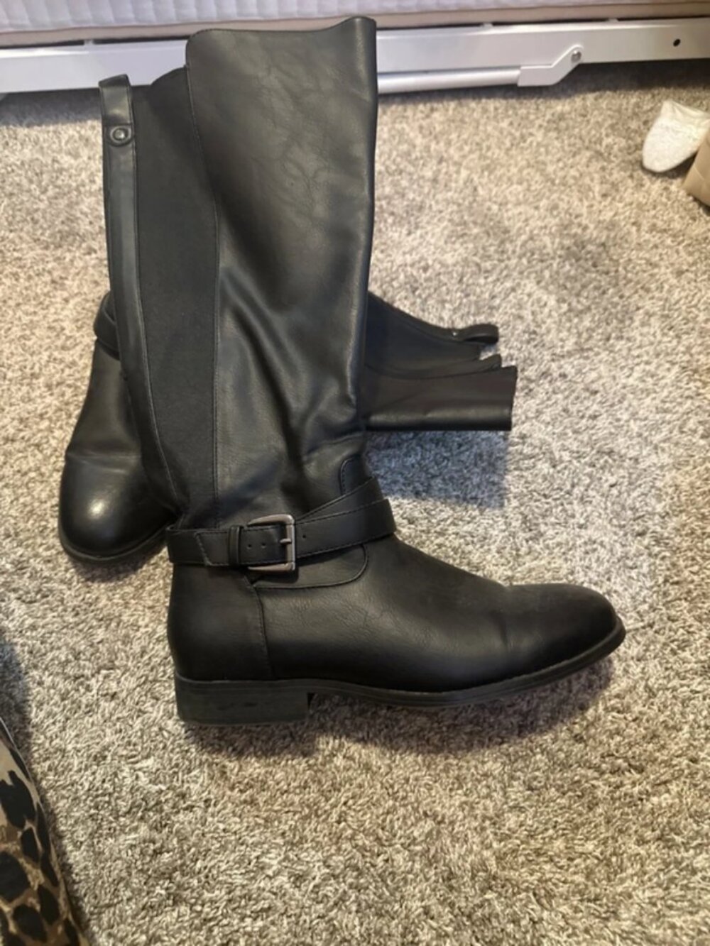 Black faux leather knee-high boots w/ a buckle detail at the ankle and a low blo